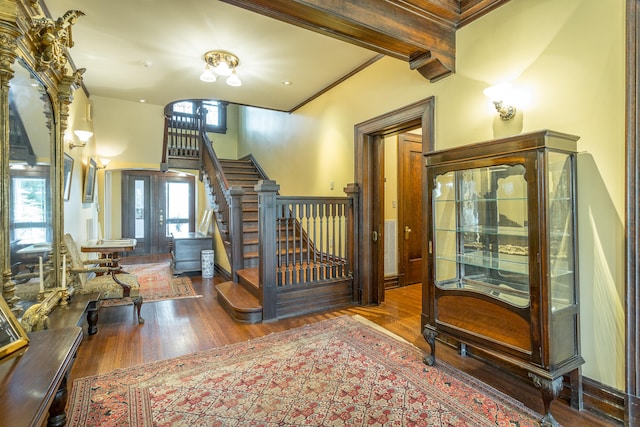 foyer featuring wood-type flooring, beam ceiling, and french doors