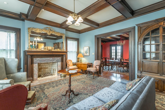 living room with beamed ceiling, coffered ceiling, a chandelier, and a high end fireplace