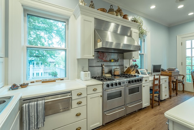 kitchen with a healthy amount of sunlight, light wood-type flooring, white cabinets, and extractor fan