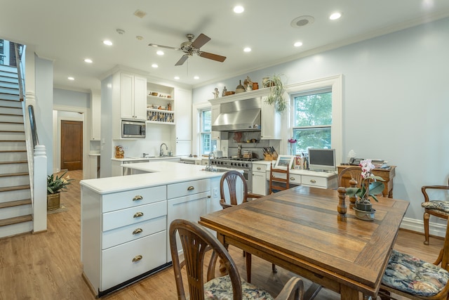 kitchen featuring light wood-type flooring, white cabinetry, extractor fan, ceiling fan, and stainless steel microwave