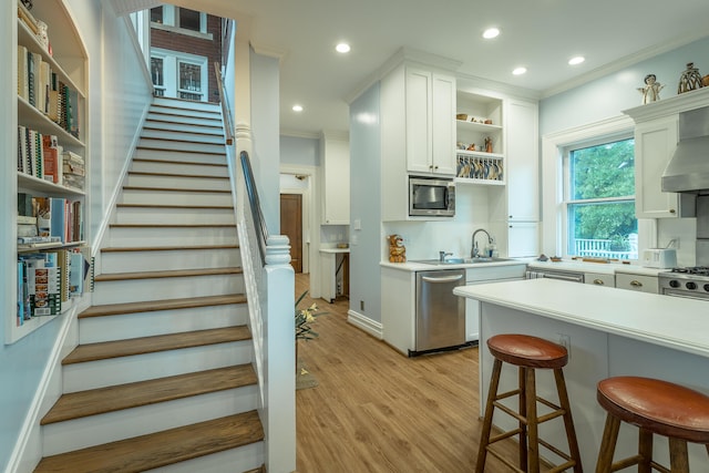 kitchen featuring light hardwood / wood-style flooring, a kitchen bar, stainless steel appliances, sink, and white cabinetry