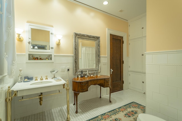 bathroom featuring crown molding, tile patterned floors, toilet, sink, and tile walls