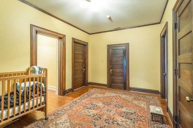 bedroom with ornamental molding and light hardwood / wood-style flooring