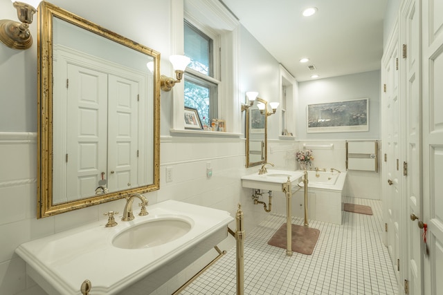 bathroom with tile patterned flooring, tile walls, sink, and a relaxing tiled tub