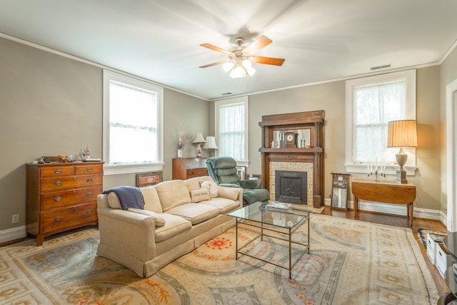 living room featuring hardwood / wood-style floors, ceiling fan, a wealth of natural light, and crown molding