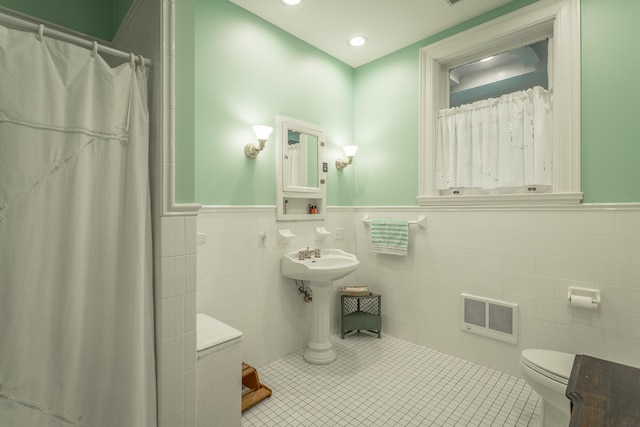 bathroom with toilet, tile patterned flooring, heating unit, tile walls, and a shower with shower curtain