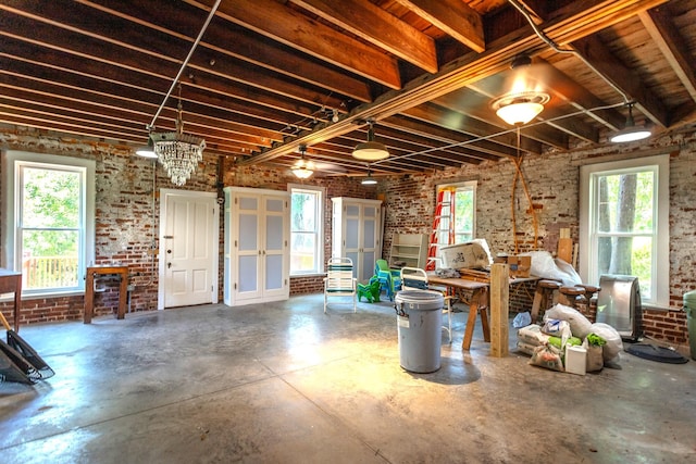 misc room featuring plenty of natural light, brick wall, and concrete flooring