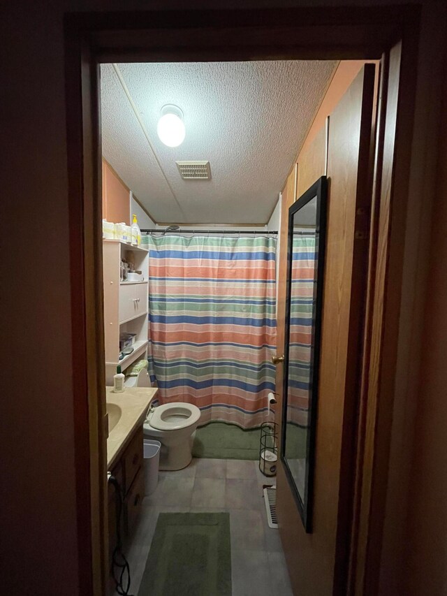 bathroom with vanity, toilet, curtained shower, and a textured ceiling