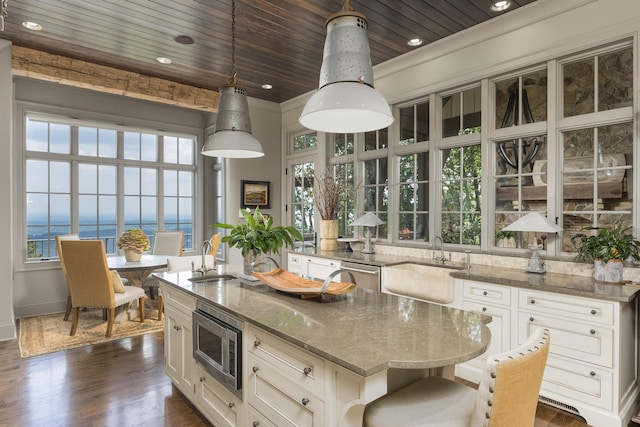 kitchen with dark wood-type flooring, plenty of natural light, stainless steel appliances, and light stone countertops