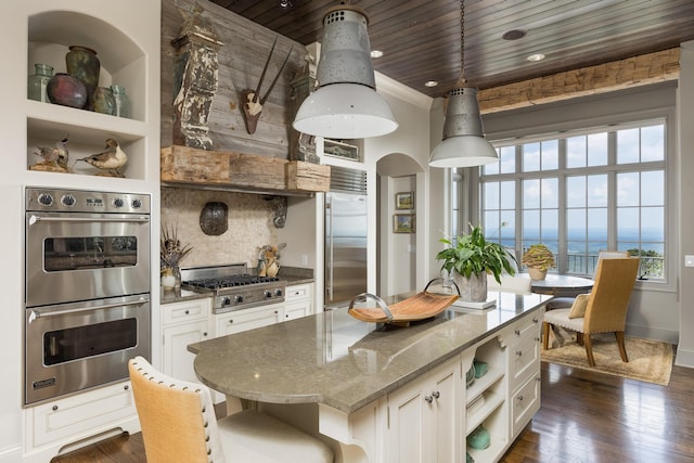 kitchen with appliances with stainless steel finishes, light stone countertops, dark hardwood / wood-style floors, and white cabinetry