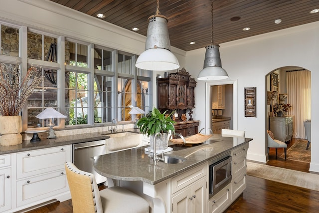 kitchen featuring dark stone countertops, wooden ceiling, stainless steel appliances, an island with sink, and dark wood-type flooring