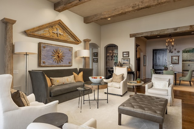 living room featuring light wood-type flooring, beam ceiling, a chandelier, and ornate columns