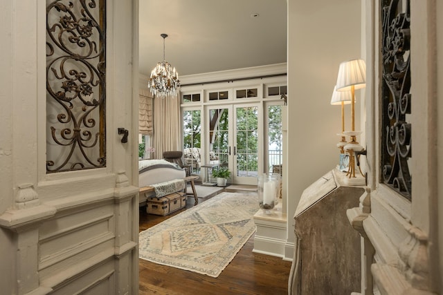 foyer with ornamental molding, a notable chandelier, and dark hardwood / wood-style floors