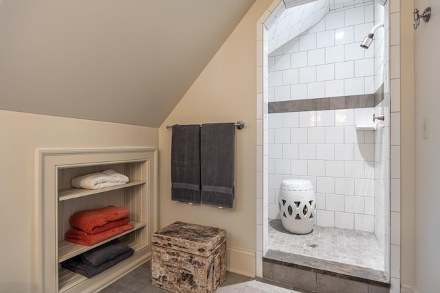 bathroom featuring lofted ceiling, tiled shower, and tile patterned floors