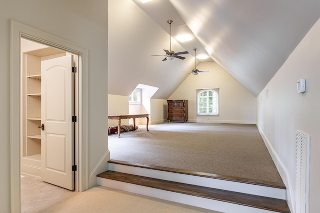 bonus room featuring built in shelves, light colored carpet, vaulted ceiling, and ceiling fan