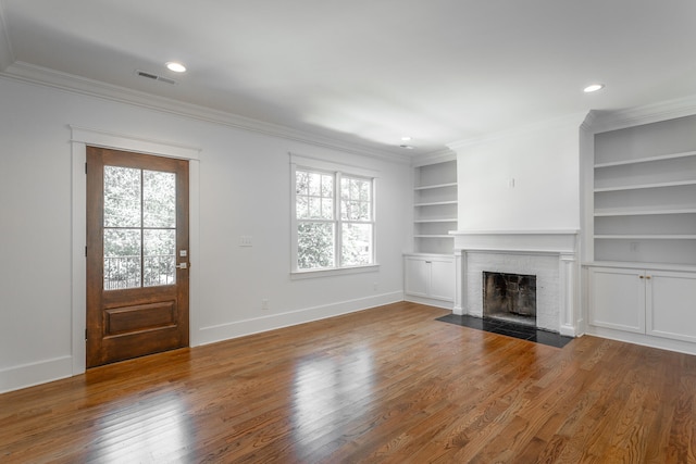 unfurnished living room with hardwood / wood-style flooring, a fireplace, and crown molding