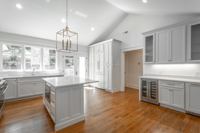 kitchen with a chandelier, light hardwood / wood-style floors, sink, wine cooler, and a kitchen island