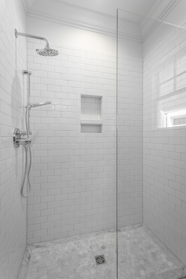 bathroom featuring a tile shower and crown molding