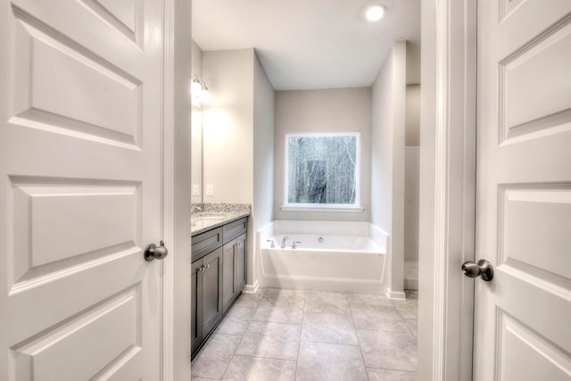 bathroom featuring tile patterned flooring, vanity, and a washtub