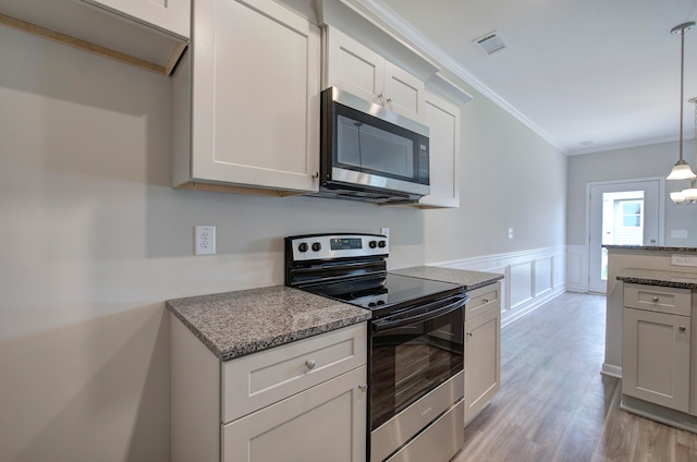 kitchen featuring dark stone countertops, decorative light fixtures, light wood-type flooring, stainless steel appliances, and white cabinetry