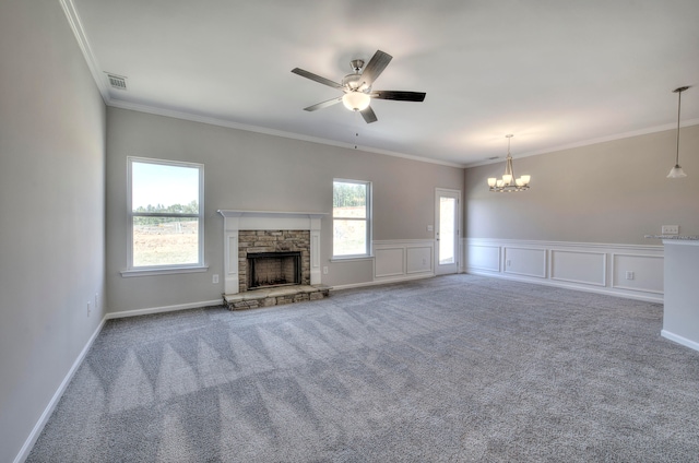 unfurnished living room with ceiling fan with notable chandelier, a wealth of natural light, ornamental molding, and a stone fireplace