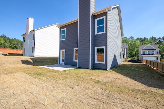 rear view of house featuring a lawn and a patio