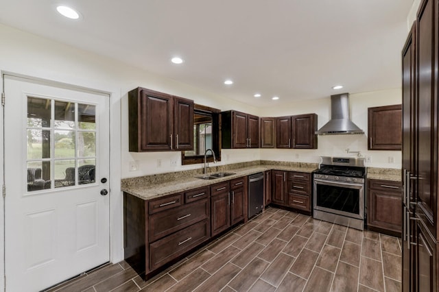 kitchen with light stone counters, stainless steel appliances, wall chimney exhaust hood, and sink