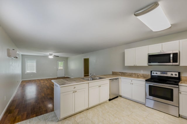 kitchen with appliances with stainless steel finishes, a wall mounted air conditioner, sink, kitchen peninsula, and ceiling fan