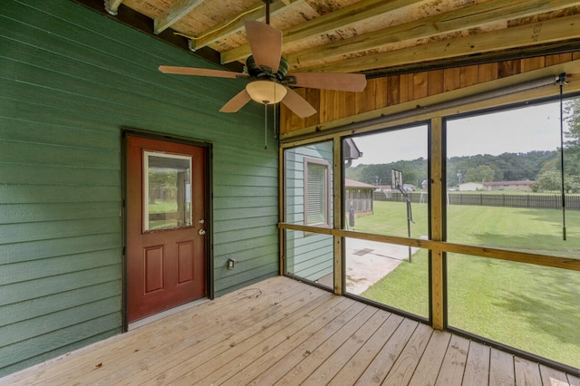 unfurnished sunroom featuring ceiling fan and beamed ceiling