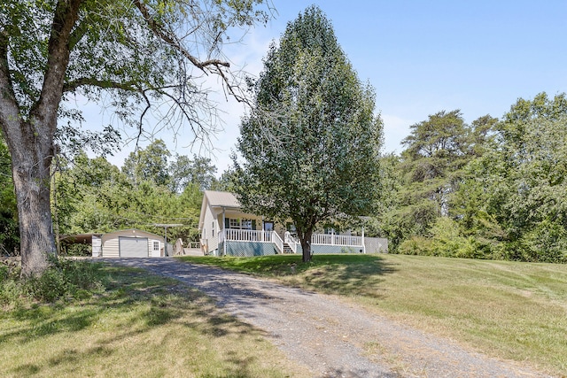 view of front of house with a garage, a front yard, a porch, and an outbuilding