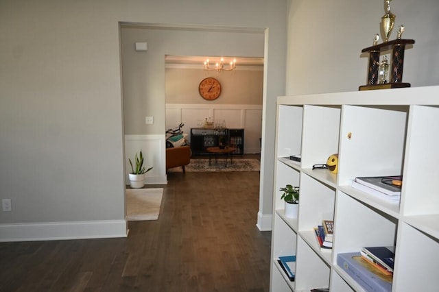 hallway featuring dark wood finished floors and an inviting chandelier