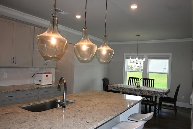 kitchen with visible vents, ornamental molding, a sink, pendant lighting, and backsplash