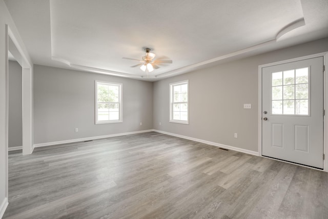 foyer entrance with a raised ceiling, ceiling fan, and light hardwood / wood-style floors