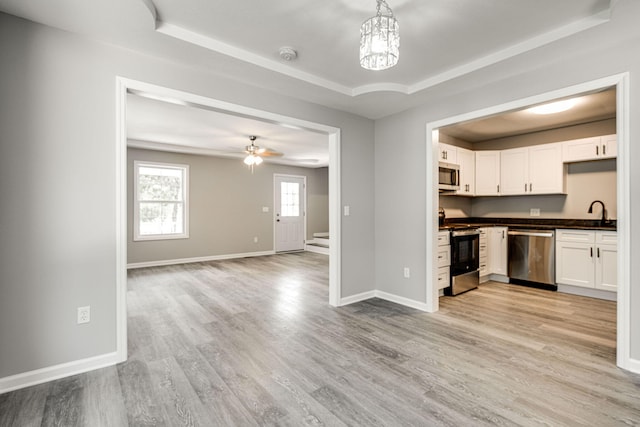 kitchen with pendant lighting, ceiling fan with notable chandelier, light hardwood / wood-style flooring, appliances with stainless steel finishes, and white cabinets