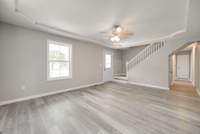 spare room with light hardwood / wood-style flooring, ceiling fan, and a raised ceiling