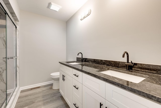 bathroom with vanity, toilet, wood-type flooring, and a shower with door