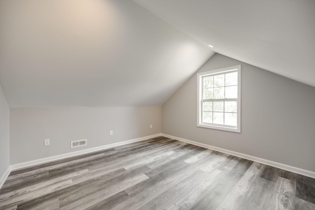 bonus room with light wood-type flooring and vaulted ceiling