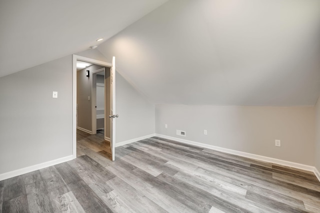 additional living space with vaulted ceiling and light hardwood / wood-style flooring