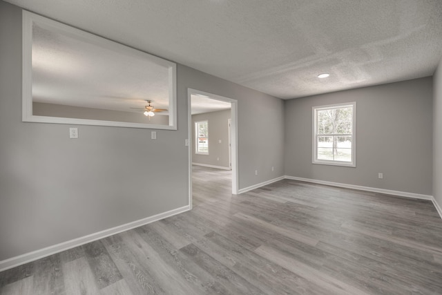 empty room with a textured ceiling, ceiling fan, and wood-type flooring