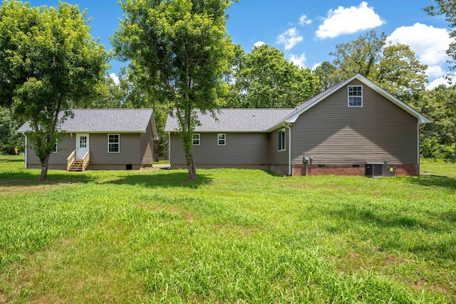 rear view of property featuring cooling unit and a lawn