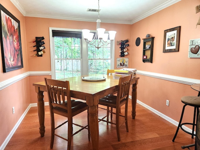 dining area with an inviting chandelier, hardwood / wood-style floors, and ornamental molding