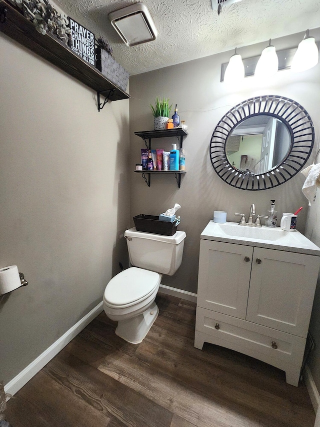 bathroom featuring vanity, wood-type flooring, toilet, and a textured ceiling