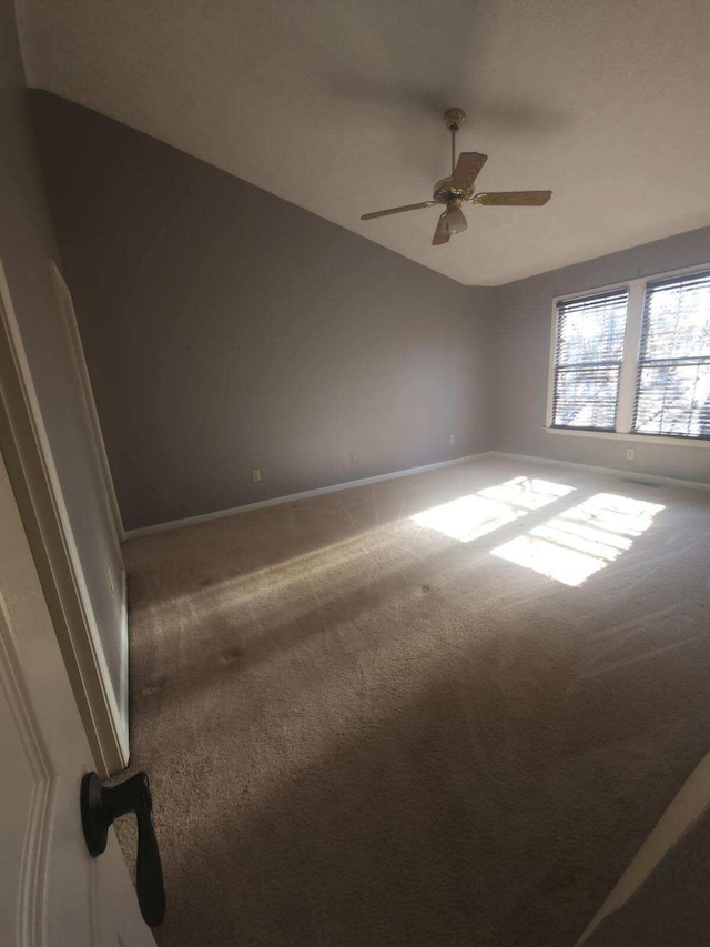 carpeted empty room featuring vaulted ceiling and ceiling fan