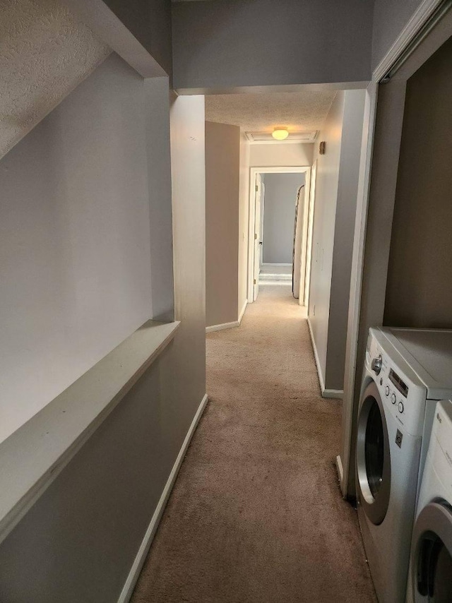 corridor featuring separate washer and dryer, light colored carpet, and a textured ceiling