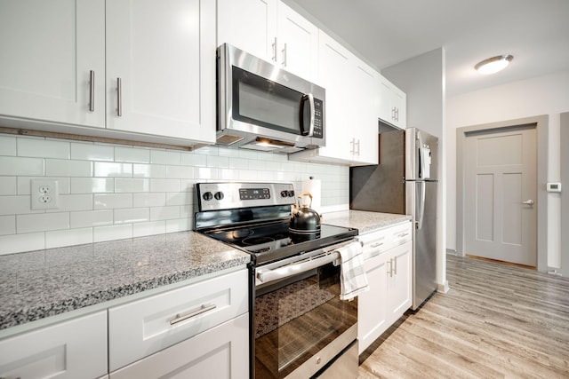 kitchen with light wood-type flooring, light stone counters, stainless steel appliances, and white cabinetry