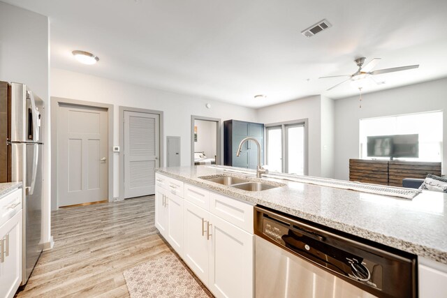 kitchen with light hardwood / wood-style flooring, appliances with stainless steel finishes, white cabinetry, sink, and ceiling fan