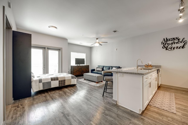 kitchen featuring white cabinetry, sink, dark wood-type flooring, ceiling fan, and a breakfast bar