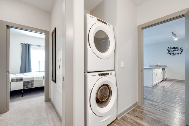 laundry area featuring light hardwood / wood-style flooring, sink, and stacked washing maching and dryer