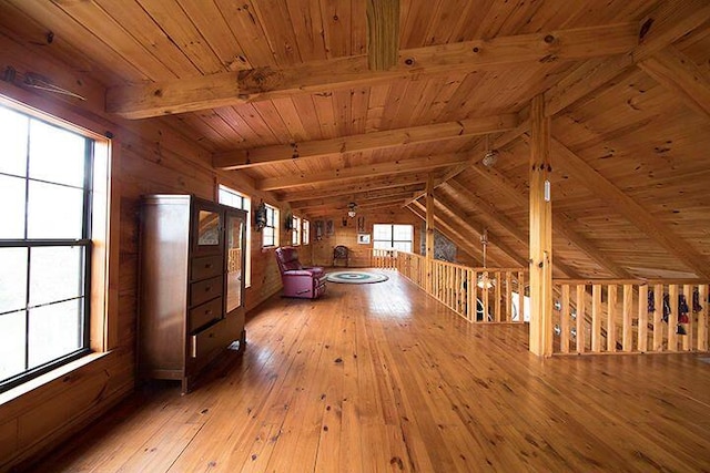 additional living space featuring vaulted ceiling with beams, wood walls, hardwood / wood-style floors, and wooden ceiling