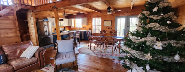 living room with wooden walls, wood-type flooring, ceiling fan, wood ceiling, and beam ceiling